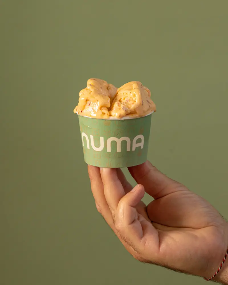 Coppetta Numa verde salvia con gelato artigianale, tenuta in mano